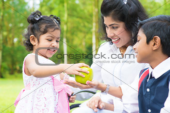 Indian girl sharing apple with family
