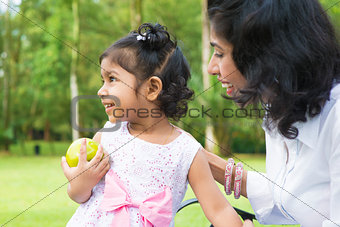 Indian girl holding an green apple outdoor