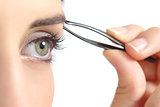 Close up of a woman eye and a hand plucking eyebrows