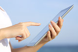 Profile of a woman hands holding and browsing a digital tablet on the beach