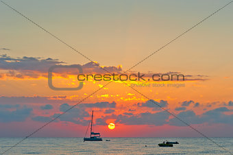 Picturesque sunset sky over the sea and the silhouettes of boats