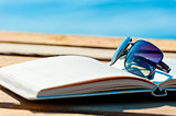 open book and sunglasses on the background of the sea