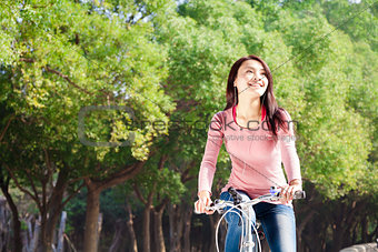 Pretty young woman riding bike in the park