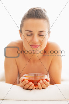 Happy young woman laying on massage table with honey plate