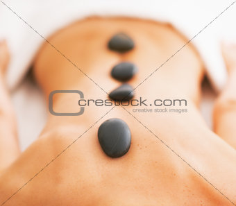 Closeup on young woman receiving hot stone massage