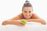 Young woman with apple laying on massage table