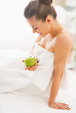 Happy young woman with apple sitting on massage table