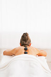 Young woman receiving hot stone massage. rear view