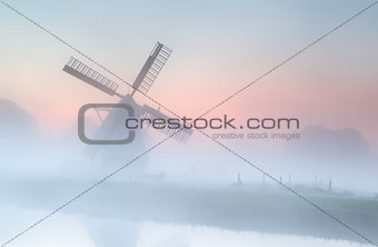 windmill in dense fog at summer sunrise