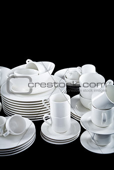 mixed white dishes cups and plates isolated on black