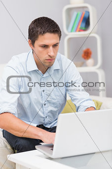Serious man using laptop at home