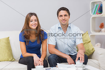 Portrait of a smiling young couple with bills at home