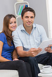 Smiling couple with bills in living room at home