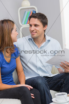 Smiling young couple with bills at home