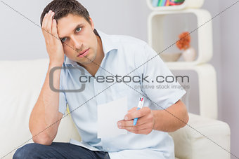 Portrait of a worried man paying his bills at home