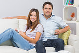 Cute couple sitting on sofa with tea cups at home