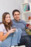 Smiling young couple with wine glasses sitting at home