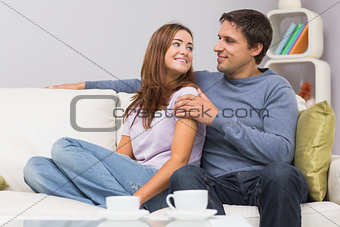 Loving couple looking at each other on sofa at home
