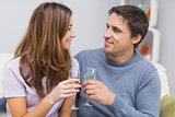 Romantic smiling young couple toasting flutes at home