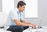 Side view of smiling man using laptop at home