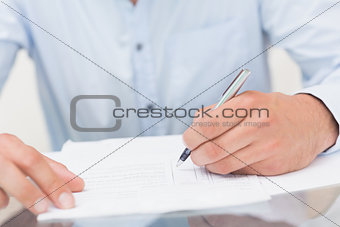 Mid section of a young man writing documents