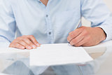 Close-up mid section of a man writing documents