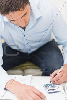 Close-up of a young man with bills and calculator