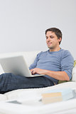 Relaxed young man using laptop in living room