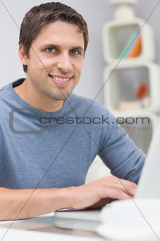 Smiling man using laptop in living room