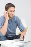Man using cellphone and laptop in living room