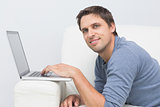 Smiling young man using laptop in living room