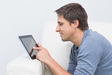 Smiling young man using digital tablet in living room