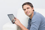 Portrait of a smiling man using digital tablet in living room
