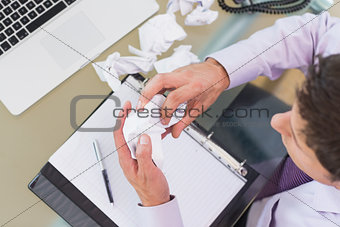 Businessman with laptop, diary and crumpled papers at office desk