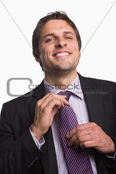 Portrait of a happy businessman adjusting tie
