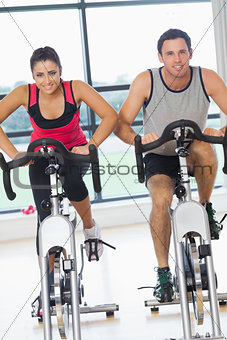 Young man and woman working out at spinning class