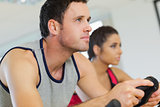 Yyoung man and woman working out at spinning class