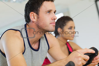 Yyoung man and woman working out at spinning class