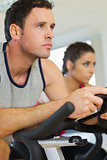 Young man and woman working out at spinning class