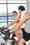 Young woman and man working out at spinning class