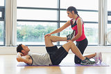 Female trainer assisting man with his exercises in gym