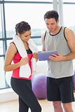 Fit couple looking at digital table in exercise room