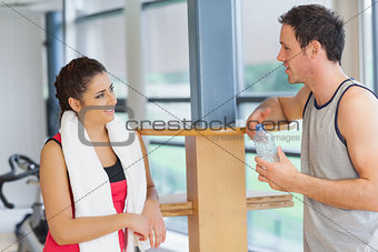 Woman and man with water bottle chatting at gym