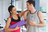 Fit couple with water bottle and exercise mat in exercise room