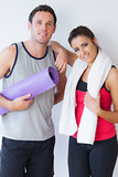 Portrait of a fit young couple with towel and exercise mat