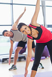 Two sporty people stretching hands at yoga class