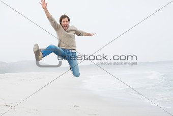 Casual young man jumping at beach