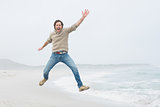 Portrait of a casual young man jumping at beach
