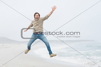 Portrait of a casual young man jumping at beach