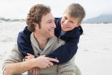 Man piggybacking his cheerful son at beach